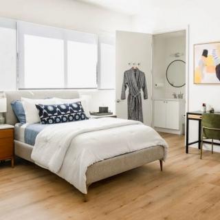 A modern and cozy bedroom with natural light streaming through large windows, featuring stylish furniture and decor.