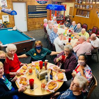 A group of elderly people enjoying a meal together in a casual setting.