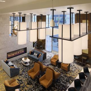 A stylish and modern living room with a large chandelier, cozy seating, and a fireplace.