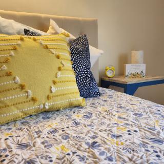 A cozy and vibrant bedroom setup featuring decorative pillows and a floral bedding pattern.