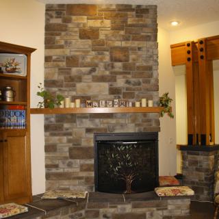 A stone fireplace in a cozy living room decorated with candles.