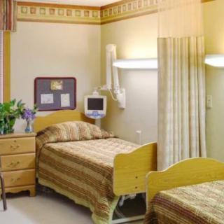 A hospital room with twin beds, medical equipment, and a decorative touch.