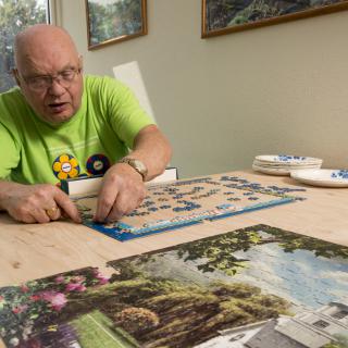 A man working on a puzzle at a table indoors.