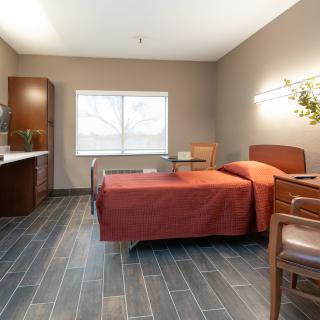 A modern and minimalistic bedroom with a single bed, chair, and window.