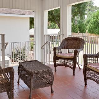 A cozy outdoor porch with wicker chairs and a table, perfect for relaxation.