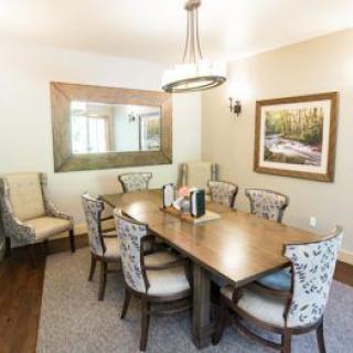 A cozy dining room with a wooden table, upholstered chairs, and elegant decor.
