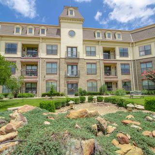 A beautiful apartment complex with a well-maintained garden and clear blue sky.