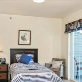 A cozy bedroom with a single bed, bedside table, and artwork on the wall.