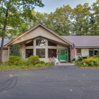 A single-story house surrounded by trees with a spacious driveway.