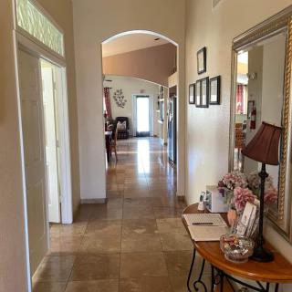 A well-decorated hallway with a mirror, lamp, and table, leading to rooms through an arched doorway.