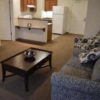 A cozy apartment living space featuring a sofa, coffee table, and a small kitchen area.
