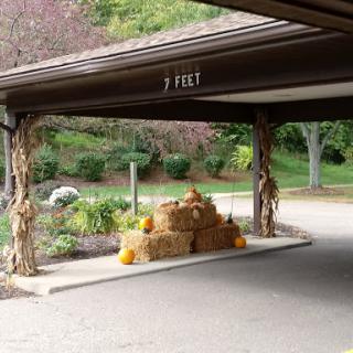 A cozy autumn display with hay bales and pumpkins under a covered area.