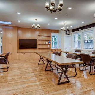 A spacious conference room with wooden floors, modern furniture, and chandeliers, designed for meetings.