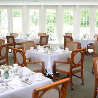 An elegant dining room with neatly arranged tables and chairs, set for a meal.