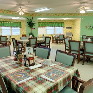 A cozy dining area with neatly arranged tables and chairs, featuring colorful tablecloths and warm lighting.