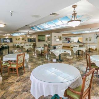 A spacious and elegantly decorated dining area with round tables covered in white tablecloths and stylish chairs.