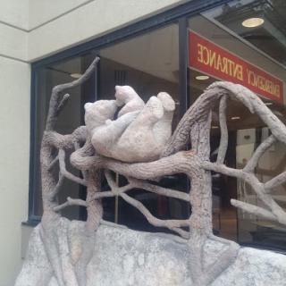 A creative sculpture featuring a resting figure intertwined with tree branches.