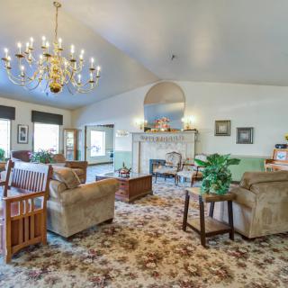 A traditionally styled living room with a chandelier, fireplace, and cozy seating area.