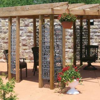 A cozy pergola with outdoor furniture and decorative planters in a garden setting.