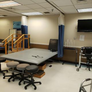 A rehabilitation room equipped for physical therapy sessions, featuring various exercise stations and a TV for patient engagement.