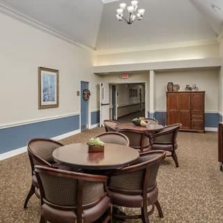 A cozy lounge area with tables and chairs, leading to a hallway.