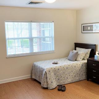 A cozy bedroom with a single bed and a nightstand, featuring minimalistic decor.