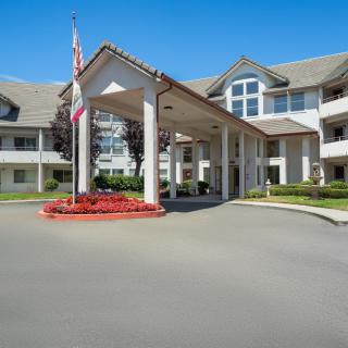 A well-maintained building entrance with landscaping and a flagpole.