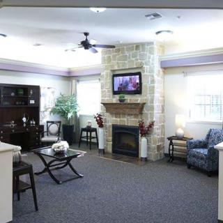 A cozy living room with a fireplace and television, featuring comfortable seating and elegant decor.