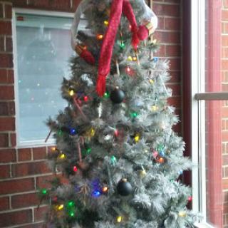 A beautifully decorated silver Christmas tree adorned with colorful lights and a festive red ribbon.