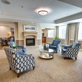 A cozy and modern living room setup featuring stylish blue upholstered chairs and a central coffee table, illuminated by natural light.