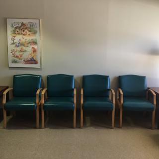 A row of teal chairs in a waiting area.
