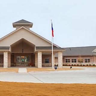 A modern school building with an entrance and a flagpole in front.