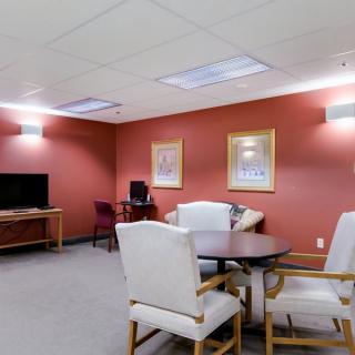 A comfortable lounge area with chairs, a table, a television, and computer station.