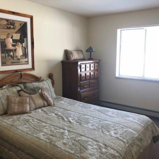 A cozy bedroom with a large bed, dresser, and artwork on the wall.