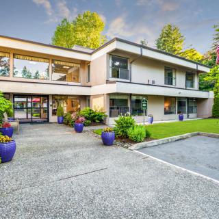 A modern two-story house with large windows, a well-maintained garden, and a spacious driveway.