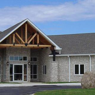 The image shows a stone building with a prominent entrance and wooden architectural accents.
