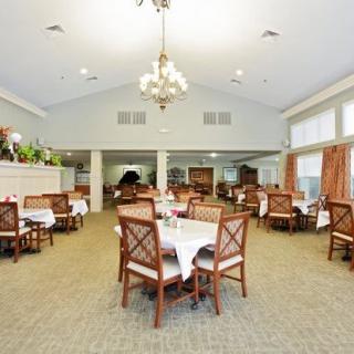 An elegant and spacious dining room with tables and chairs, featuring a central chandelier.