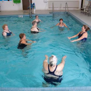 A group of women participating in an aquatic exercise class in a swimming pool.