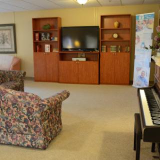 A cozy living room setup featuring a television, bookshelves, comfortable seating, and a piano.