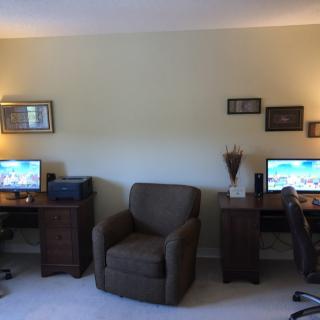 A cozy home office setup with two workstations, featuring computers and comfortable seating.