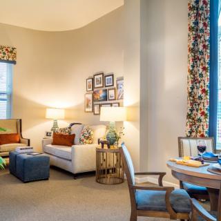 A cozy living room featuring a white sofa, colorful curtains, and warm lighting.