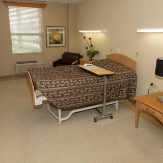 A clean and organized hospital room with a bed and essential furniture.