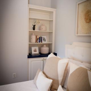 A cozy bedroom with a white bookshelf and neutral-toned decor.