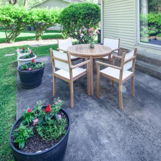 A cozy outdoor patio setup with a round table, four chairs, and decorative planters.
