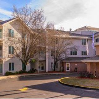 A residential apartment building with a driveway and trees in the foreground.