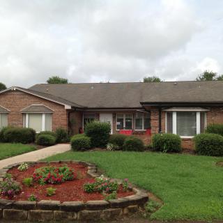 A brick house with a well-maintained lawn and garden.
