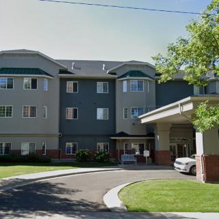 A multi-story residential building with a driveway and landscaped surroundings.