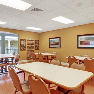 A community dining area with tables and chairs, featuring warm lighting and decorated walls.