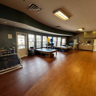 A spacious interior designed for rehabilitation and exercise, featuring therapy tables and ample natural light.