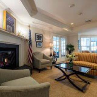 A cozy living room featuring a fireplace, elegant furniture, and an American flag.